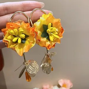 Close-up of vibrant orange fabric flower earrings with glass drop pendant and silver needle
