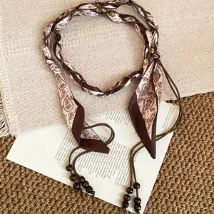 Detailed view of boho waist chain with paisley silk ribbon and wooden bead tassels