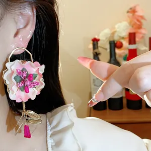 Close-up of elegant oversized pink fabric flower earrings with vibrant glass drop details.