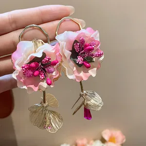 Detailed view of handmade pink fabric flower earrings with metallic leaves and glass beads