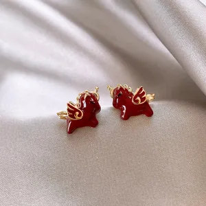 Macro dei dettagli in smalto rosso e ali dorate degli orecchini a forma di cavallo