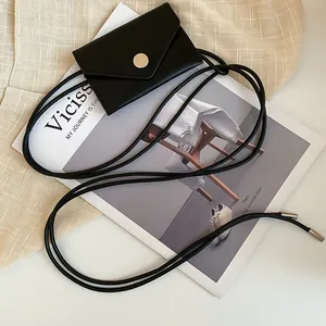 Close-up of minimalist black faux leather mini belt pouch on a fashion magazine background