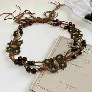 Close-up of vintage ethnic woven belt with wooden beads and butterfly metal ornaments