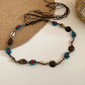 Detail view of Bohemian woven waist chain featuring natural shells and blue flower beads