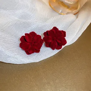 Dettaglio di orecchini a lobo a fiore in velluto rosso dal design elegante e raffinato.
