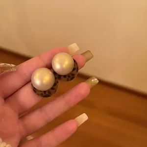 Close-up of pearl stud earrings with a stylish leopard print base detail