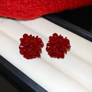 Detail view of elegant red enamel flower stud earrings displayed in a white jewelry box