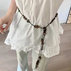 Boho vintage style waist chain with wooden beads and long tassel detail shown on model