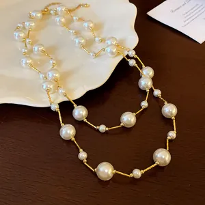 Detalle de un collar de perlas vintage con barras doradas texturizadas para mujer.