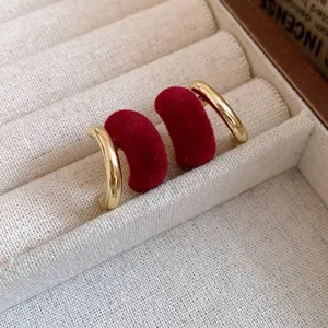 Primo piano di orecchini a fagiolo in velluto rosso con un elegante design in metallo dorato