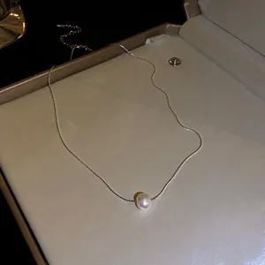 Gros plan d'un collier de perles d'eau douce minimaliste avec chaîne dorée