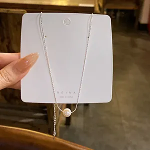 Détail en gros plan d'un collier en chaîne d'argent avec une seule perle blanche