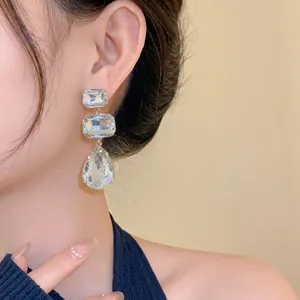 Eleganti orecchini con strass quadrati e a goccia indossati da una modella asiatica.