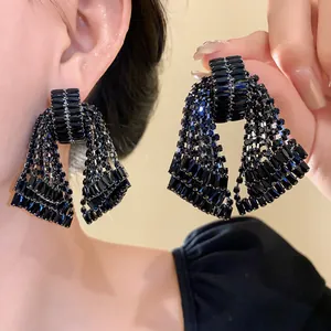 Macro view showing the sparkling black rhinestone detail of these bow tassel earrings