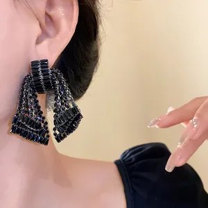 Close-up of elegant black bow-shaped crystal tassel earrings worn on an Asian model