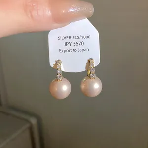 Macro view of French vintage pink pearl drop earrings with crystal studs on card