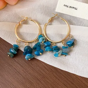 Close-up detail view of gold hoop earrings with hanging irregular blue stone bead tassels