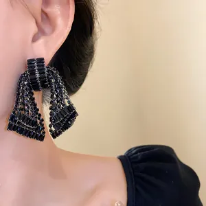 Luxury black rhinestone bow tassel earrings shown as a close-up on model's ear detail