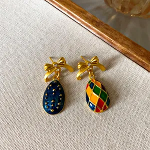 Nahaufnahme von asymmetrischen Emaille-Schleifenohrringen im Vintage-Stil.
