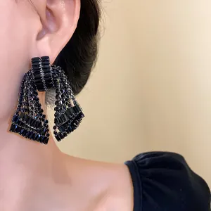 Detailed close-up of a glamorous black crystal bow tassel earring worn by a model