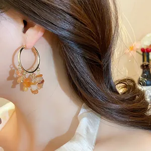 Detail view of gold hoop earrings with irregular colorful stone tassels on model