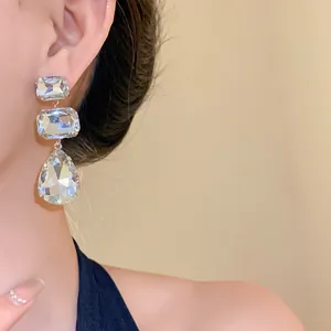Dettaglio di orecchini a nappa color argento con strass sfaccettati quadrati e a goccia.