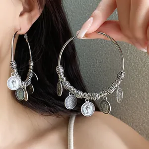 Dettaglio di orecchini a cerchio vintage color argento con ciondoli moneta Regina
