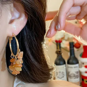 Close-up of irregular amber stone tassel hoop earrings on model.