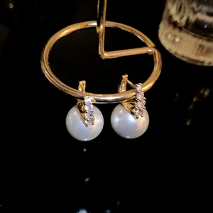 Close-up of gold hoop earrings with white pearls and sparkling crystals on a display stand