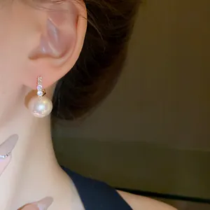 Elegant pink pearl earrings with sparkling diamond accents worn on ear for women