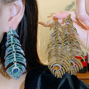 Close-up detail of exquisite rhinestone-studded feather earrings in blue and gold colors