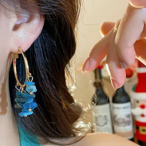 Close-up of ethnic style hoop earrings with irregular blue stone tassels worn on ear