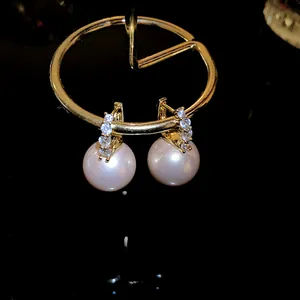 Close-up of elegant pink pearl earrings with sparkling rhinestones in gold finish