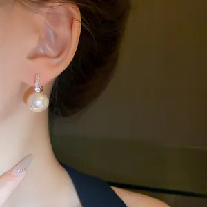 Close-up of elegant French vintage huggie earrings with pink pearl and diamonds.