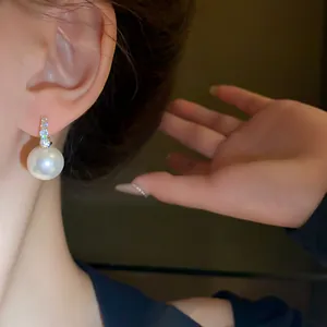 Close-up detail of a French retro pearl earring with sparkling crystals on a model's ear.