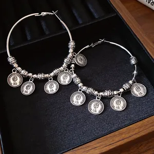 Dettaglio di orecchini a cerchio retrò in argento con ciondoli a moneta della Regina Elisabetta.
