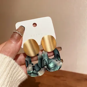 Large geometric marble acetate hoop earrings with golden oval brushed metal studs.