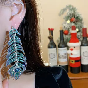 Close-up view of a large feather-shaped earring encrusted with blue and green crystals
