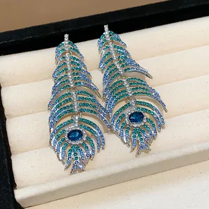 Detailed macro shot of feather-shaped stud earrings with blue and teal crystals