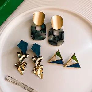Detailed macro view showing three pairs of trendy geometric acrylic and gold earrings