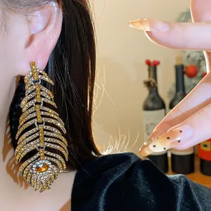 Close-up of luxury sparkling gold rhinestone feather earrings on model with black velvet