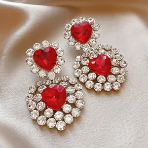 Close-up of luxury red heart crystal earrings surrounded by sparkling rhinestones