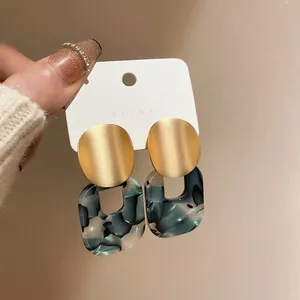 Macro detail of green marble resin and matte gold geometric earrings