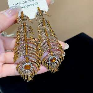 Close-up of vintage feather drop earrings with amber and white rhinestones