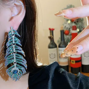 Close-up of luxury feather-shaped rhinestone earrings with vibrant blue and green gems