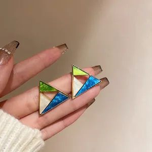 Close-up detail of geometric triangular earrings with blue, green, and white resin inlay.