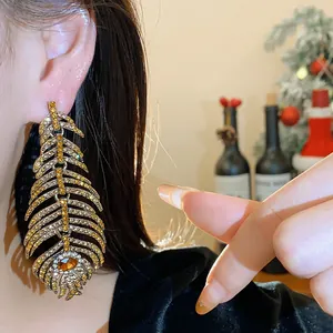Close-up detail of luxury feather-shaped earrings with sparkling yellow crystals