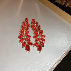 Detailed view of elegant gold-toned earrings featuring vibrant red marquise-cut crystals