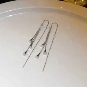 Elegant long silver tassel threader earrings with cone-shaped charms detail view