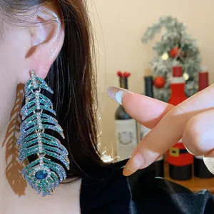 Close-up view of elegant feather drop earrings encrusted with blue and green crystals